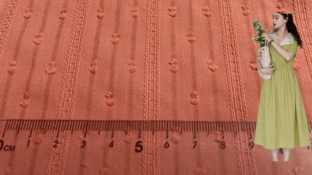 Close-up view of cotton jacquard fabric with dotted stripe pattern and intricate texture.